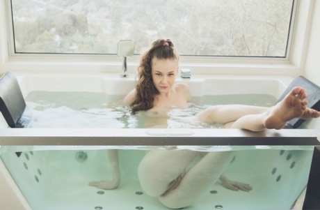 Long legged cutie squats in the glass tub pantiless spreading to show pink