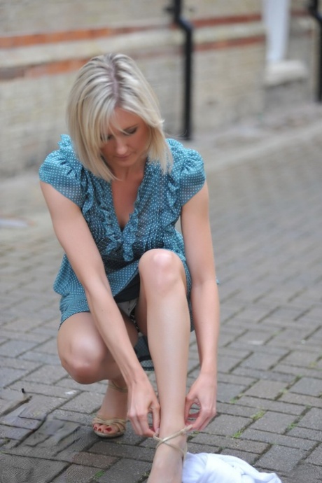 Blond solo girl with nice legs flashes her underwear before undressing at home