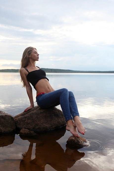 Girl next door Megan pulls out her tits while sitting on a rock in the lake
