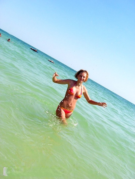 Amateur girl with red hair changes into a bikini before getting in the ocean