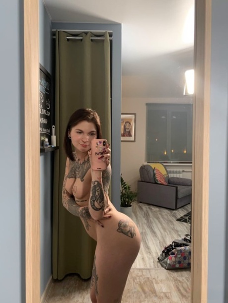 Playful brunette shows her hot tattooed body while posing in the mirror
