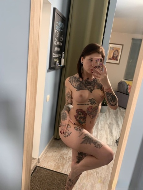 Playful brunette shows her hot tattooed body while posing in the mirror