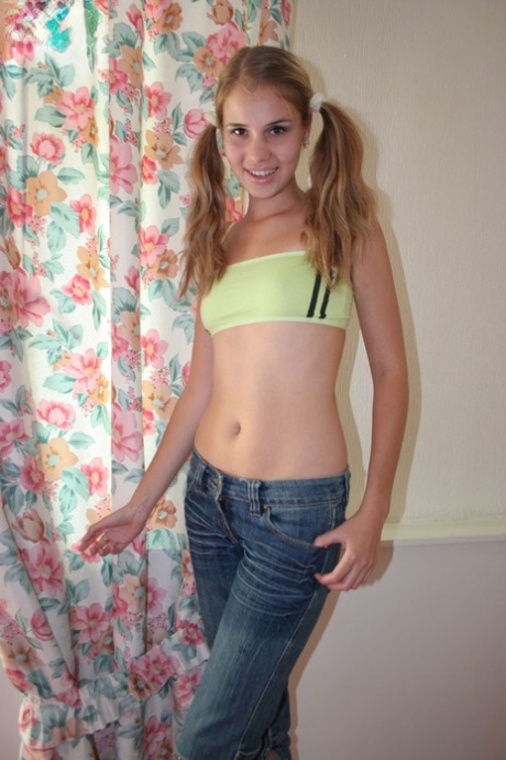 Young looking girl plays with her pigtails while stripping to her socks