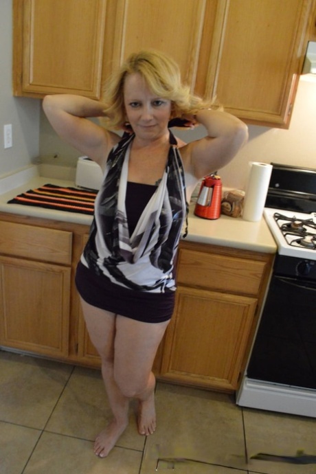 Mature blonde strips in the kitchen & rubs her juicy tits and hot pussy