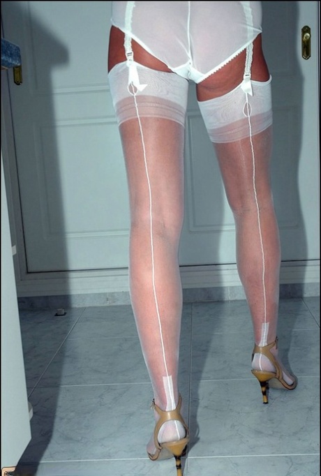 Adorable mature woman posing in white lingerie and shiny seamed stockings