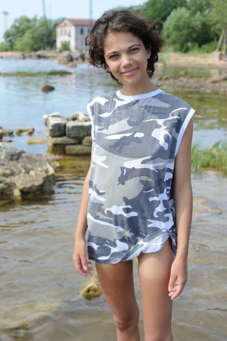 Skinny teen Tina removes sunglasses while posing naked in shallow water