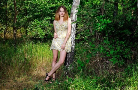 Young and busty redhead Dakota Pink showcases her bald twat in the woods