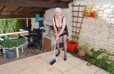 Horny granny lifts her sexy skirt to play with her beaver in the garden