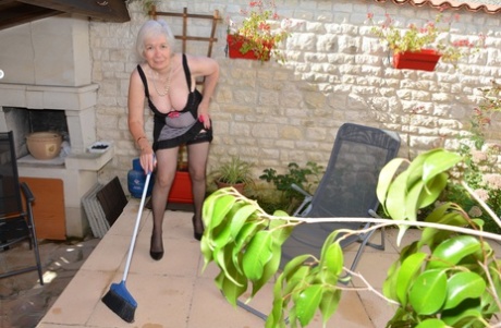 Horny granny lifts her sexy skirt to play with her beaver in the garden