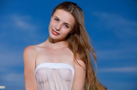 Beautiful teen Elle Tan sheds see thru attire for great nude poses atop a hill