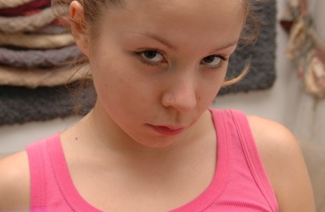 Charming young girl uncovers her small tits on a loveseat in a thong and socks