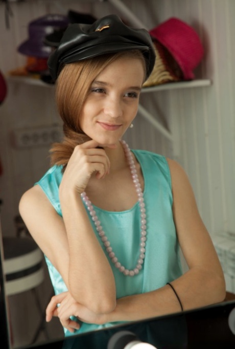 Young looking girl Alisabelle puts her hair up while getting totally naked