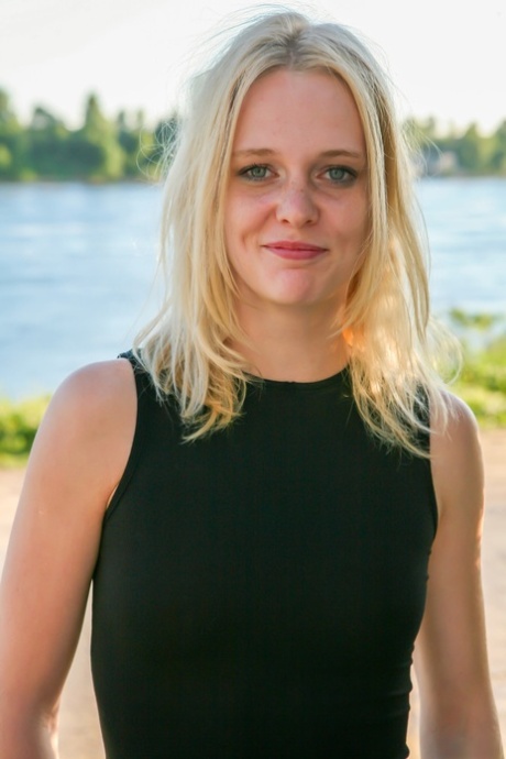 Blonde teen Petrina T lifts up her short skirt and shows her shaved pussy