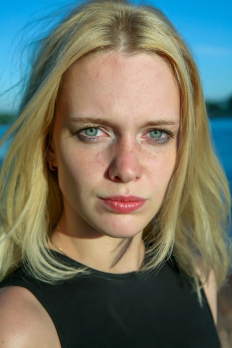 Blonde teen Petrina T lifts up her short skirt and shows her shaved pussy