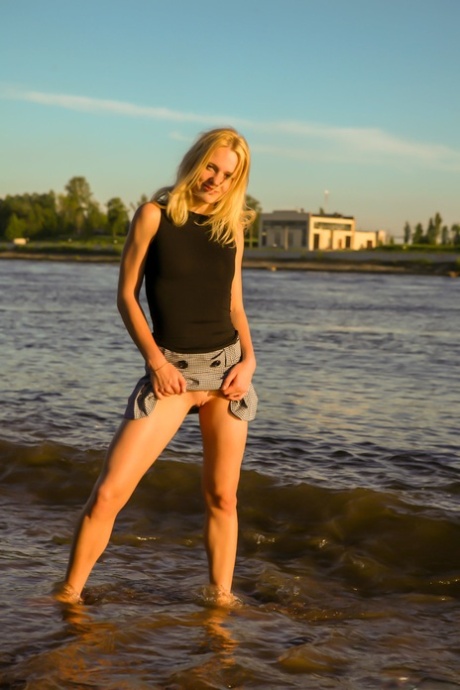 Blonde teen Petrina T lifts up her short skirt and shows her shaved pussy