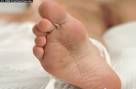 Naked amateur model is tied to a bed with a horse bit in her mouth