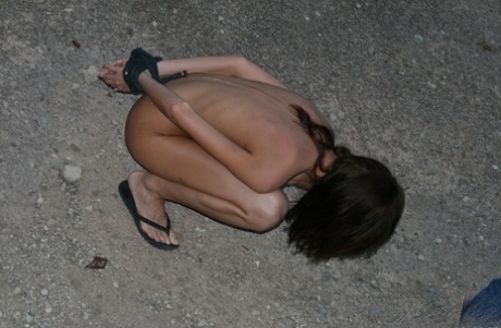 Naked slave girls are spanked and whipped by their handler outdoors