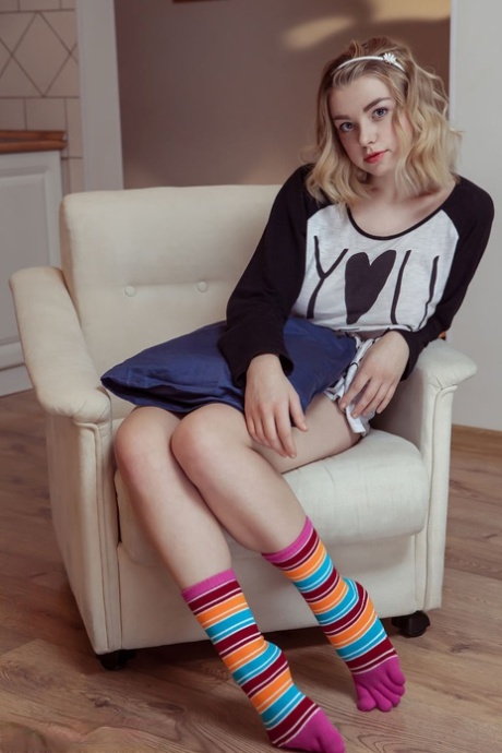 Young blonde sinks a couple of fingers in her pussy after stripping to socks